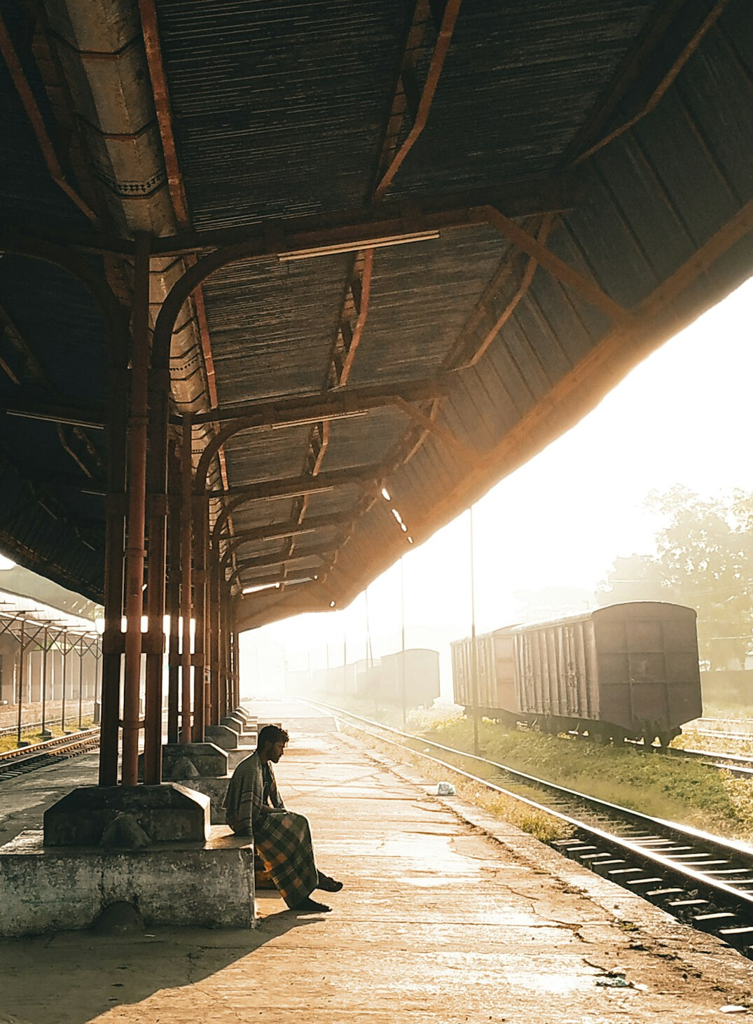 Abandoned old railway station platform at golden hour with rusty tracks